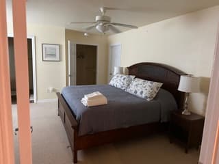 Master bedroom with queen bed, nightstand, ceiling fan, and walk-in closet entrance